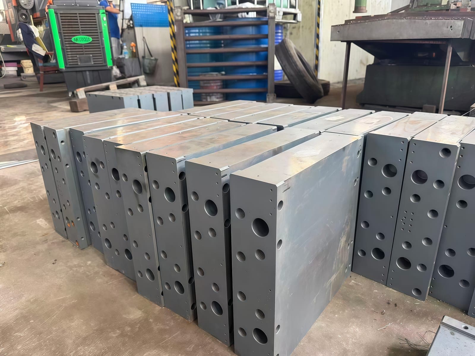 Machined steel plates with drilled features prepared in the workshop.