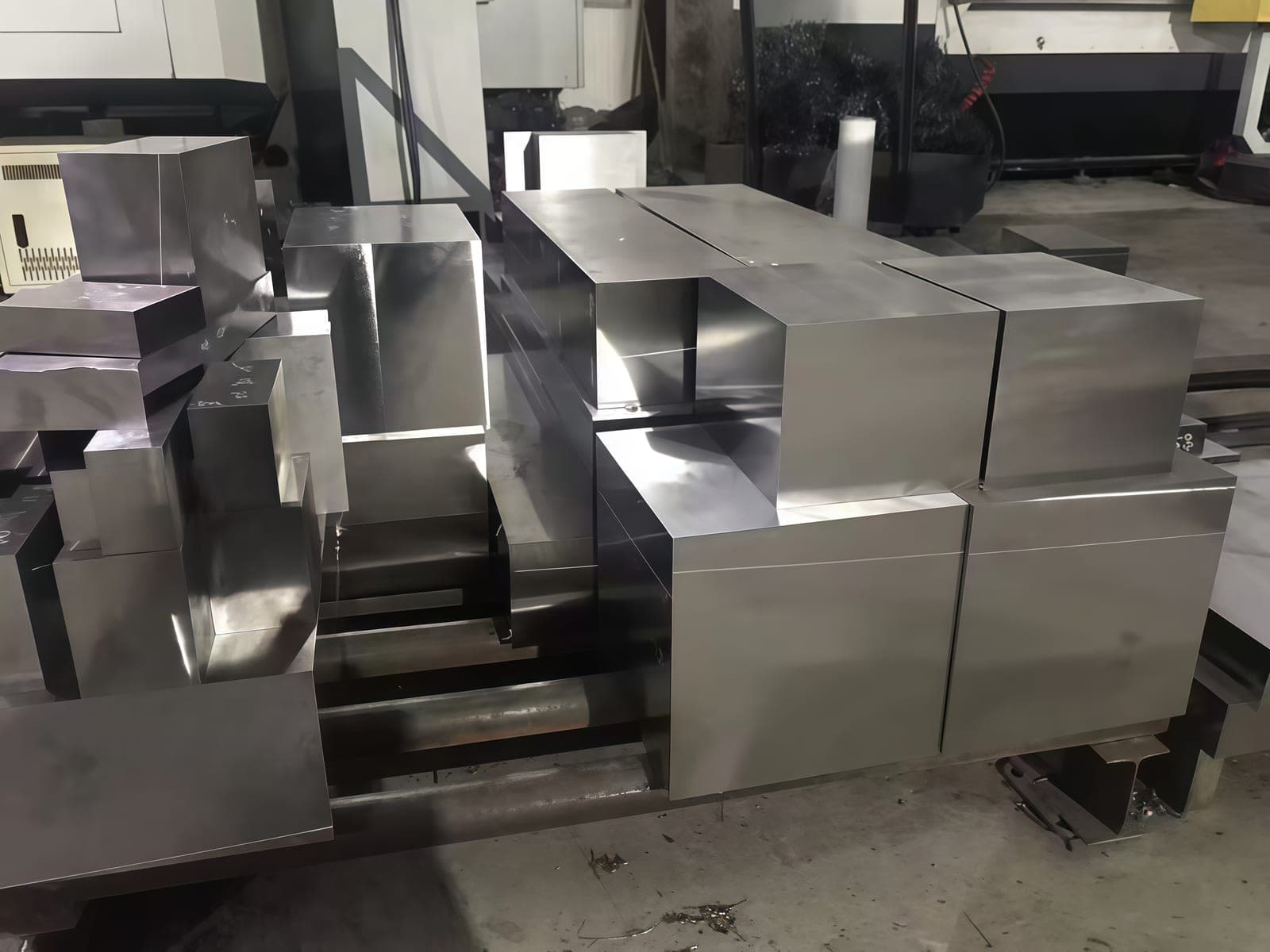 Machined and ground steel blocks beside processing equipment.
